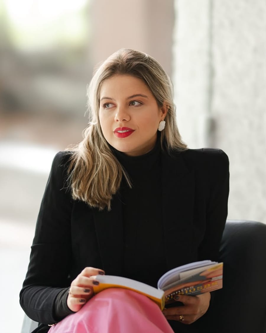 Sheila Lima sentada, segurando um livro aberto